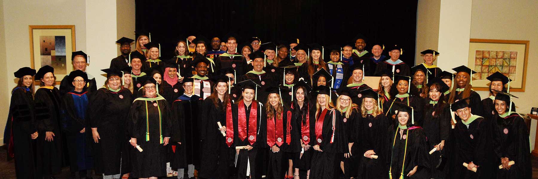 A large group of graduates pose in caps and gowns